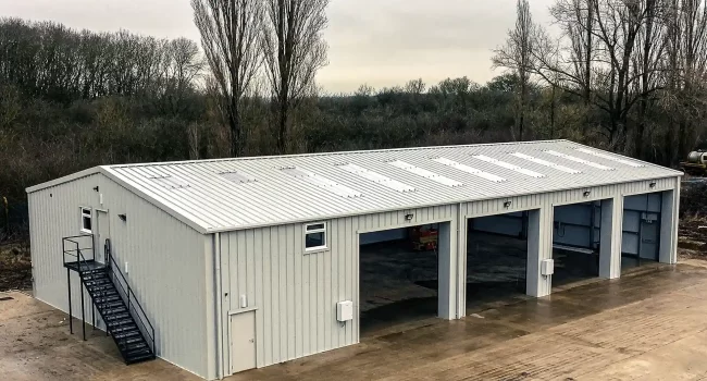 Super-Smushed Large Steel building with 4 no. Open Roller Doors, and external stairs. Clad in white Kingspan Cladding